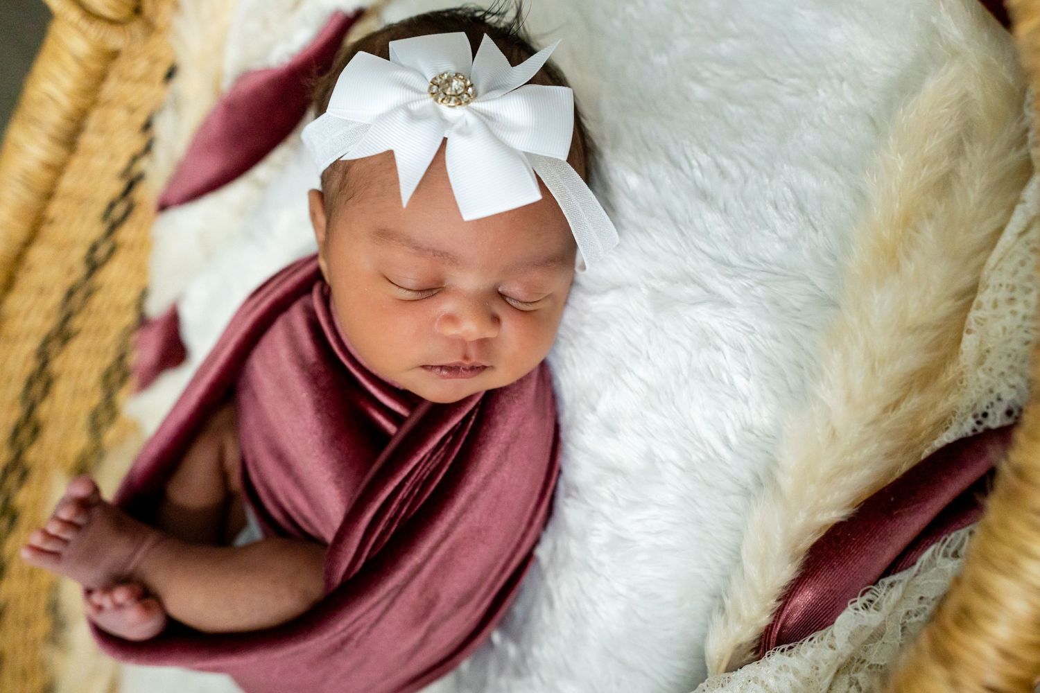 portrait of baby girl wrapped in rose velvet and sleeping in a Moses basket