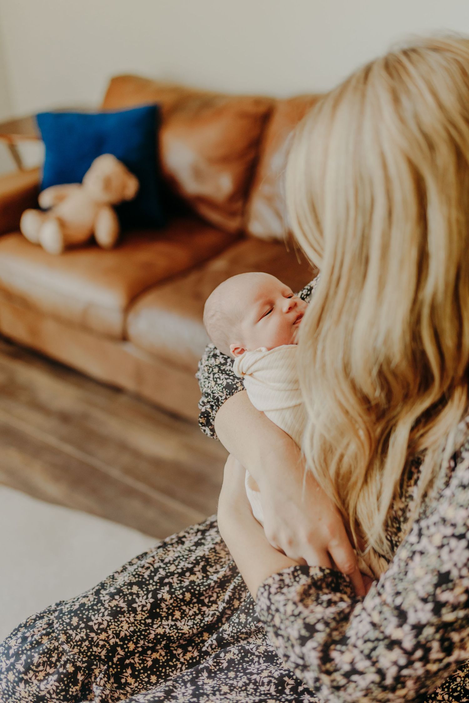 Young mother bonds with newborn during in home newborn photography session in San Diego, California.