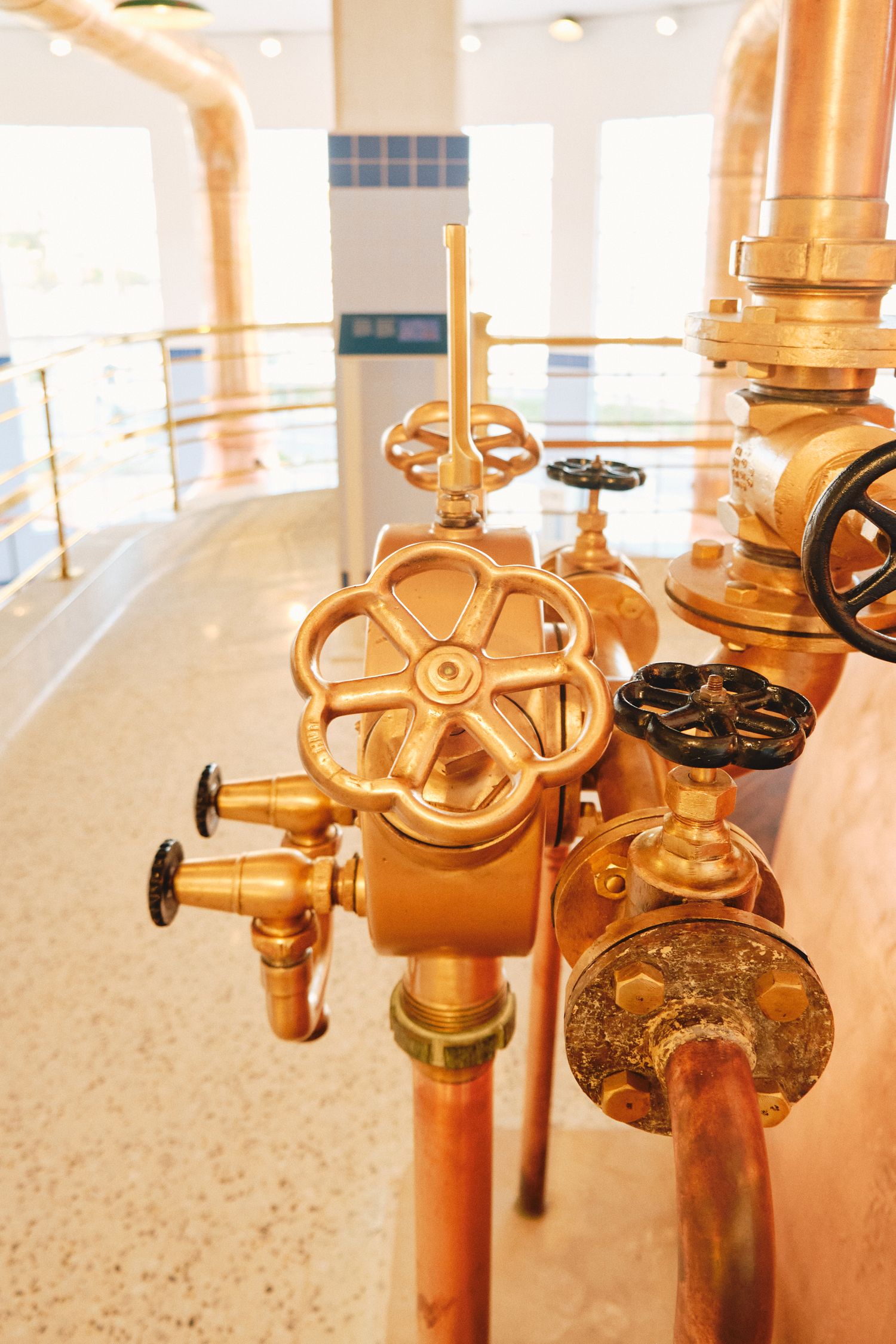 Copper brewing equipment valves and control wheels in an industrial brewery setting.