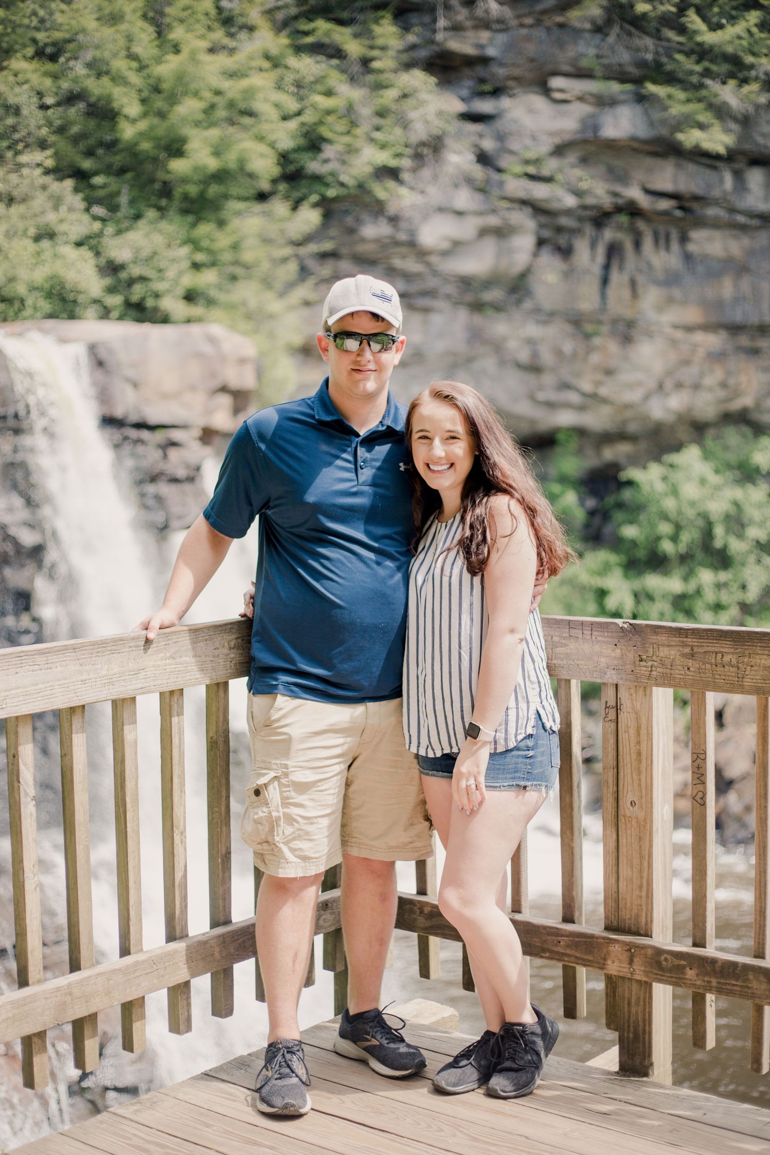 A happy couple embracing on a wooden observation deck with a stunning waterfall vista.