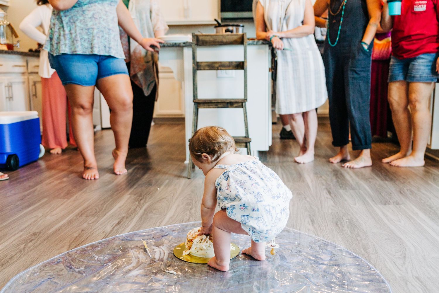 A one. year old girl eating birthday cake on the floor
