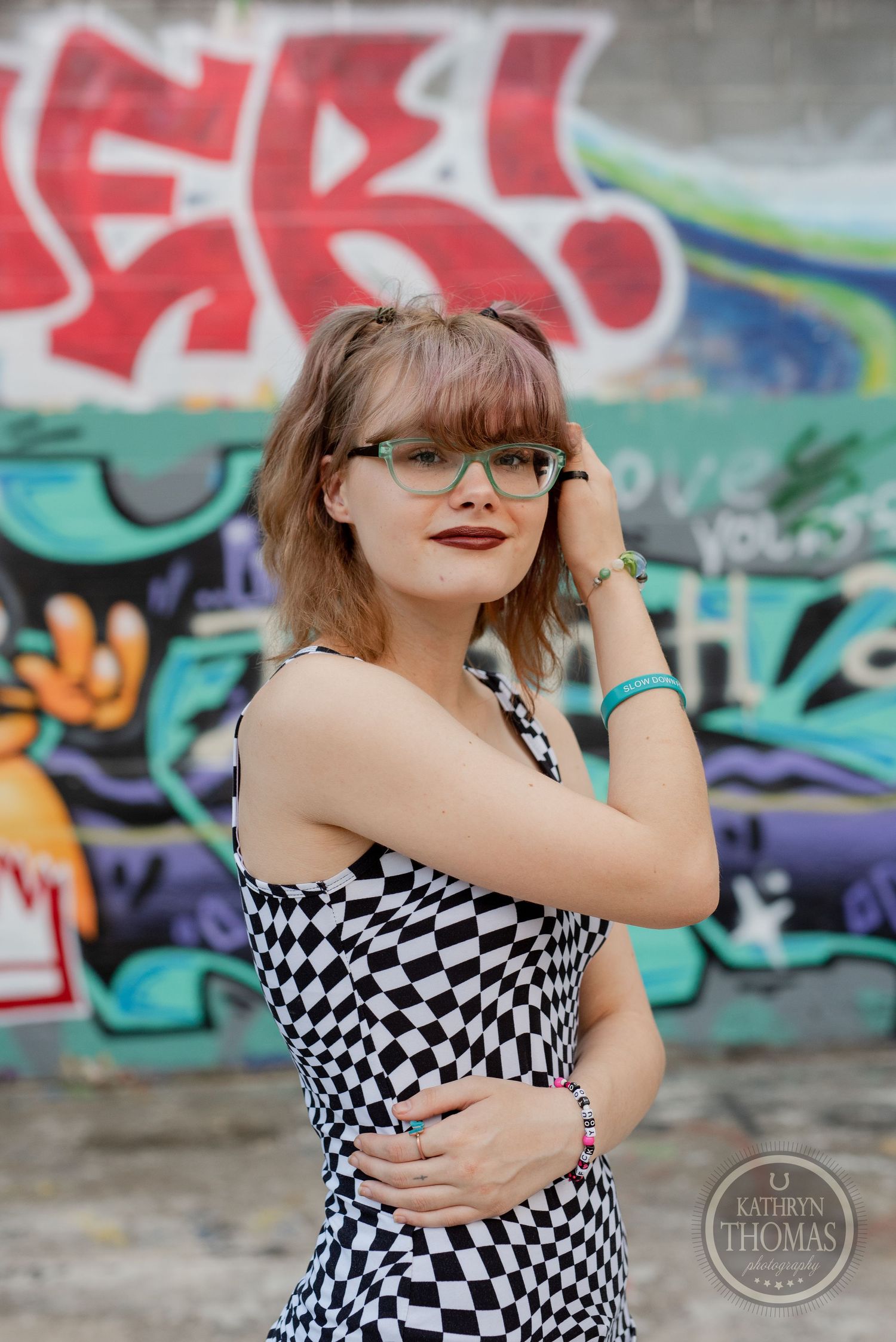 Fashion portrait featuring black and white checkered dress against colorful graffiti background.