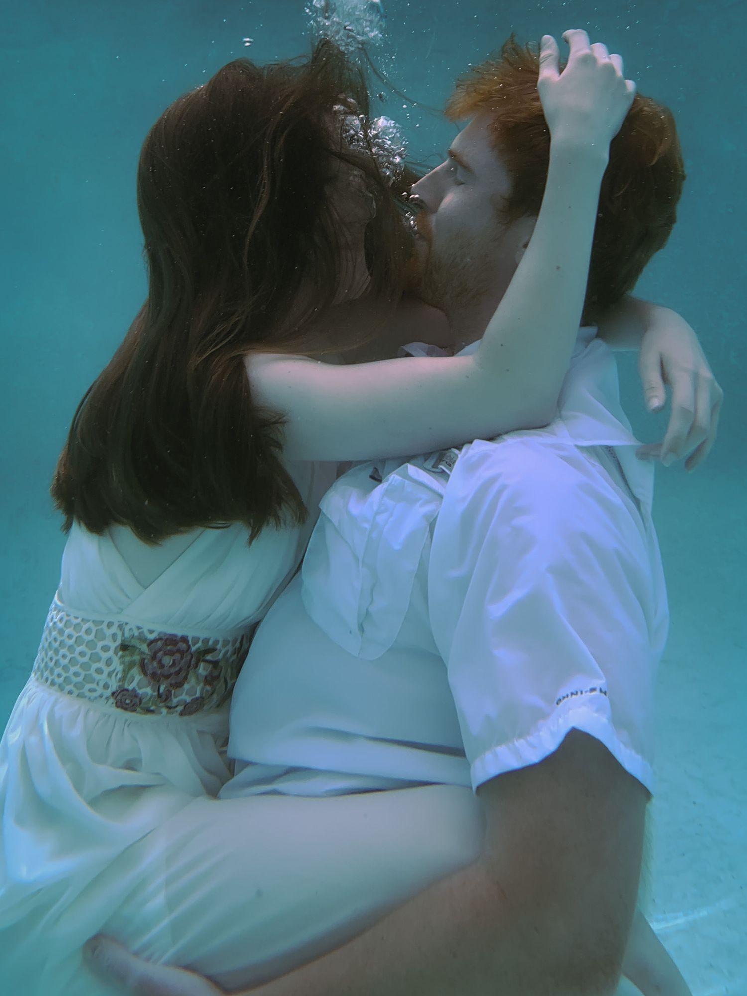 A man and a woman embrace underwater