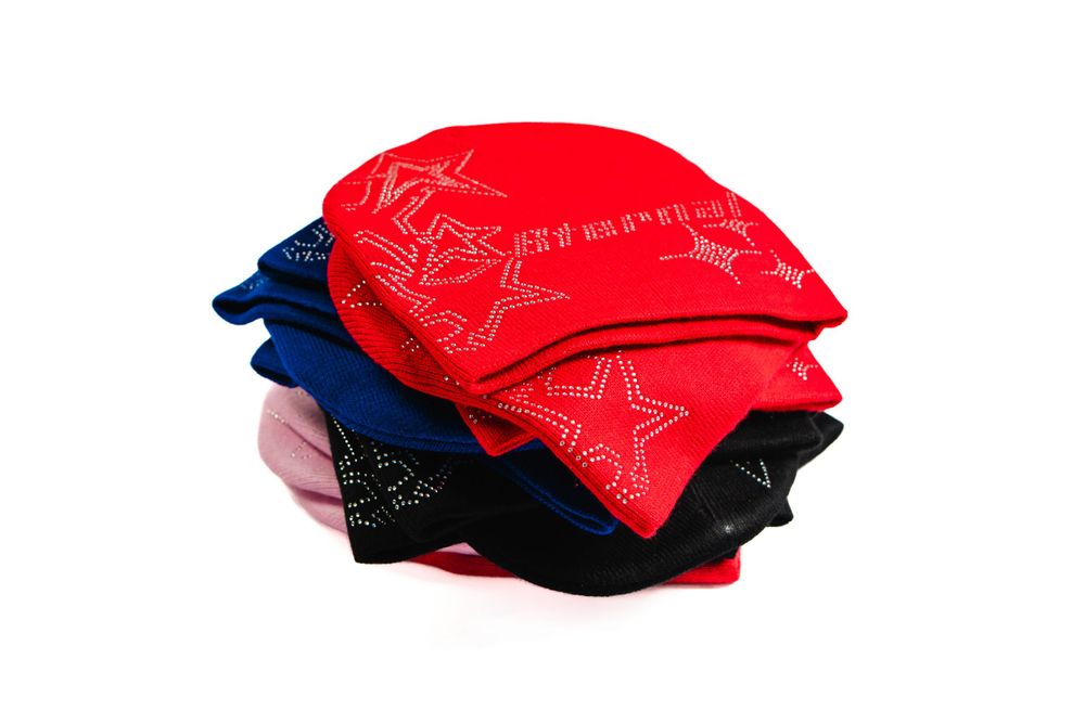 Stack of folded designer beanies in red, black, and pink — minimalist product photo by Timoy B Photography.