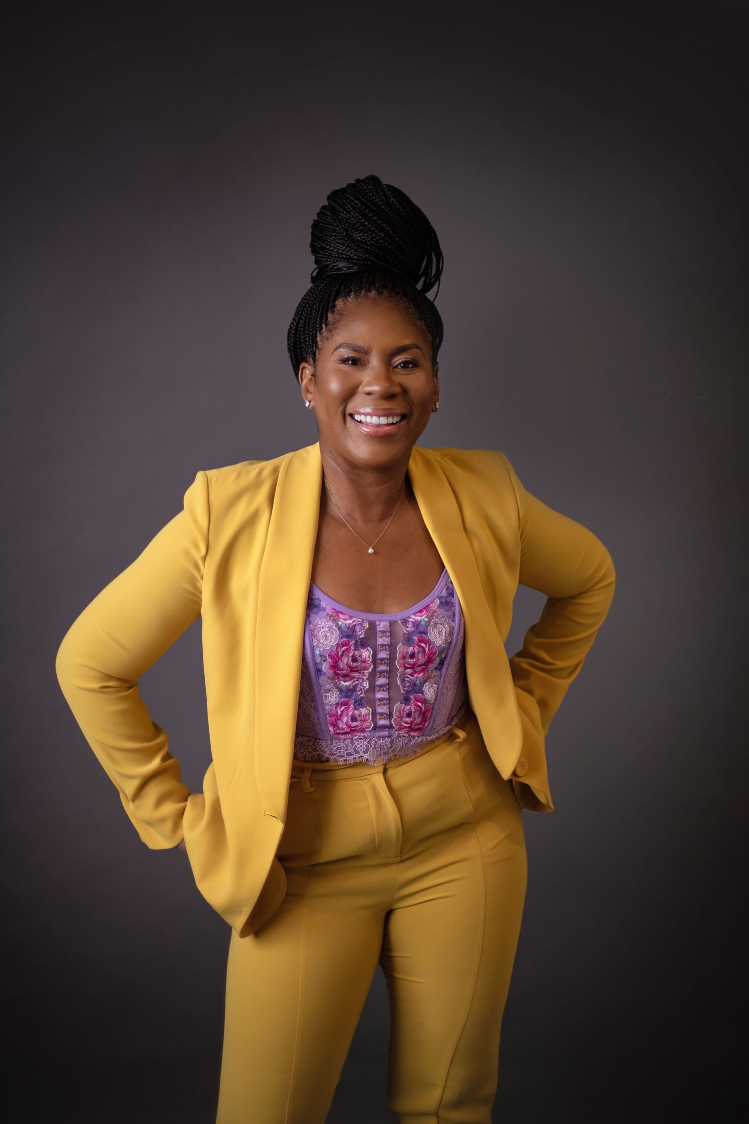 Professional portrait series showing vibrant yellow business suit and floral top against dark background.