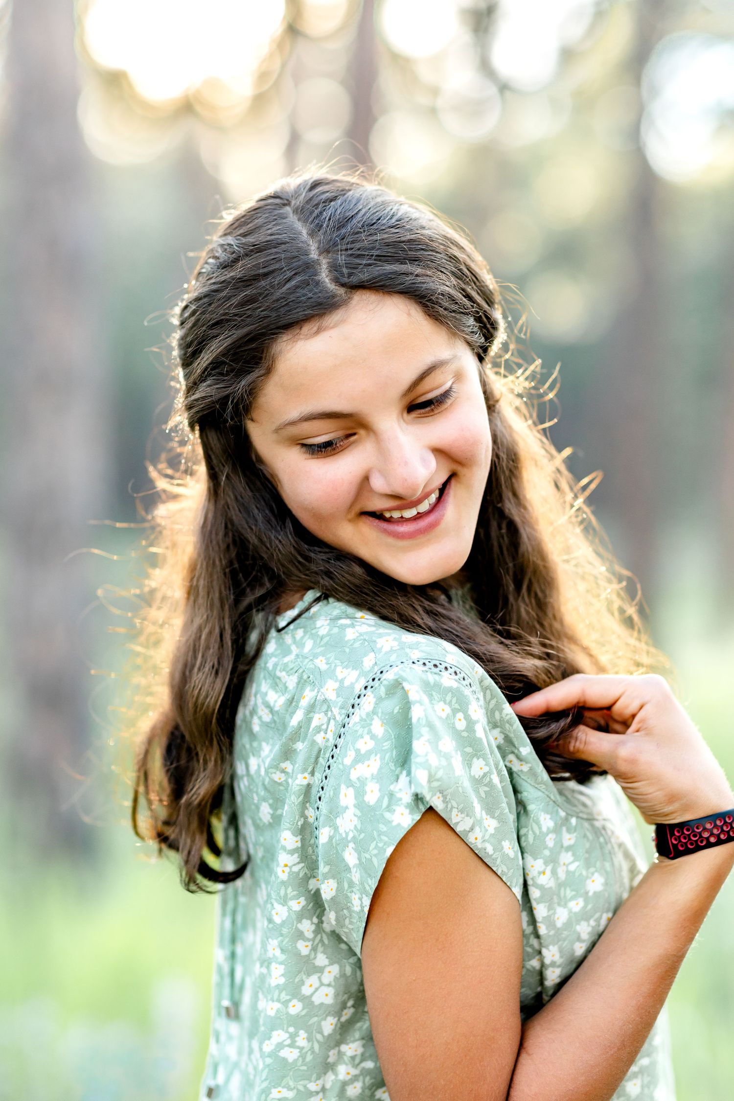 Teen girl smiles over her shoulder and plays with her hair during their family session in Colorado Springs.
