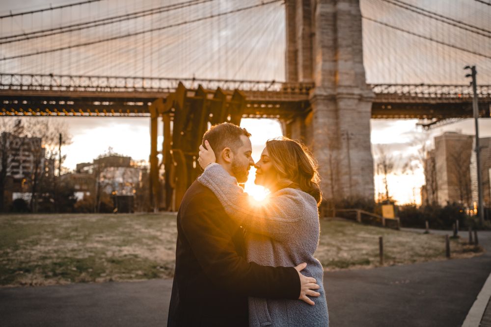 Romantic sunset engagement photos captured beneath the Brooklyn Bridge with dramatic lighting.