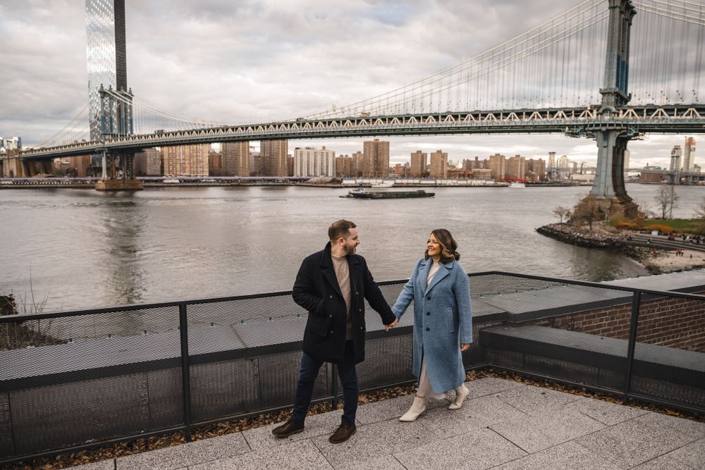 A scenic waterfront promenade with city skyline and bridge in the background.