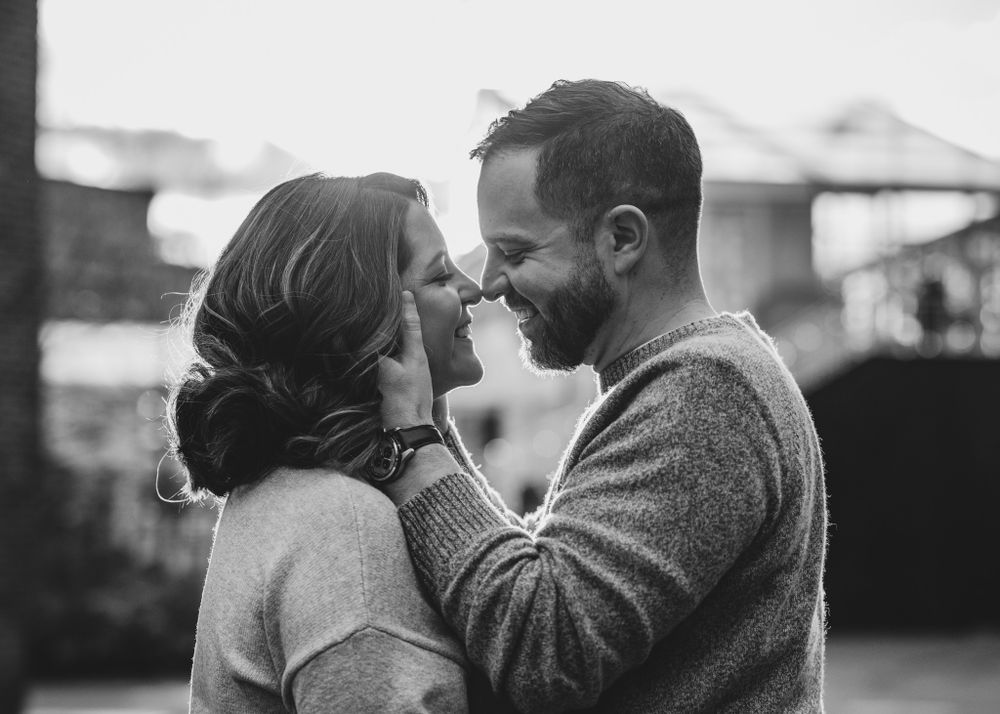 A black and white portrait of a couple sharing an intimate moment outdoors.
