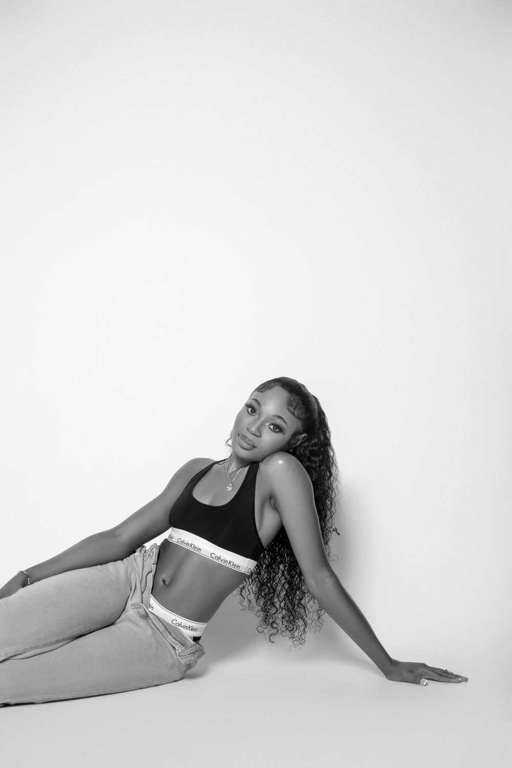 Black and white portrait of model in athletic wear posing on white background.