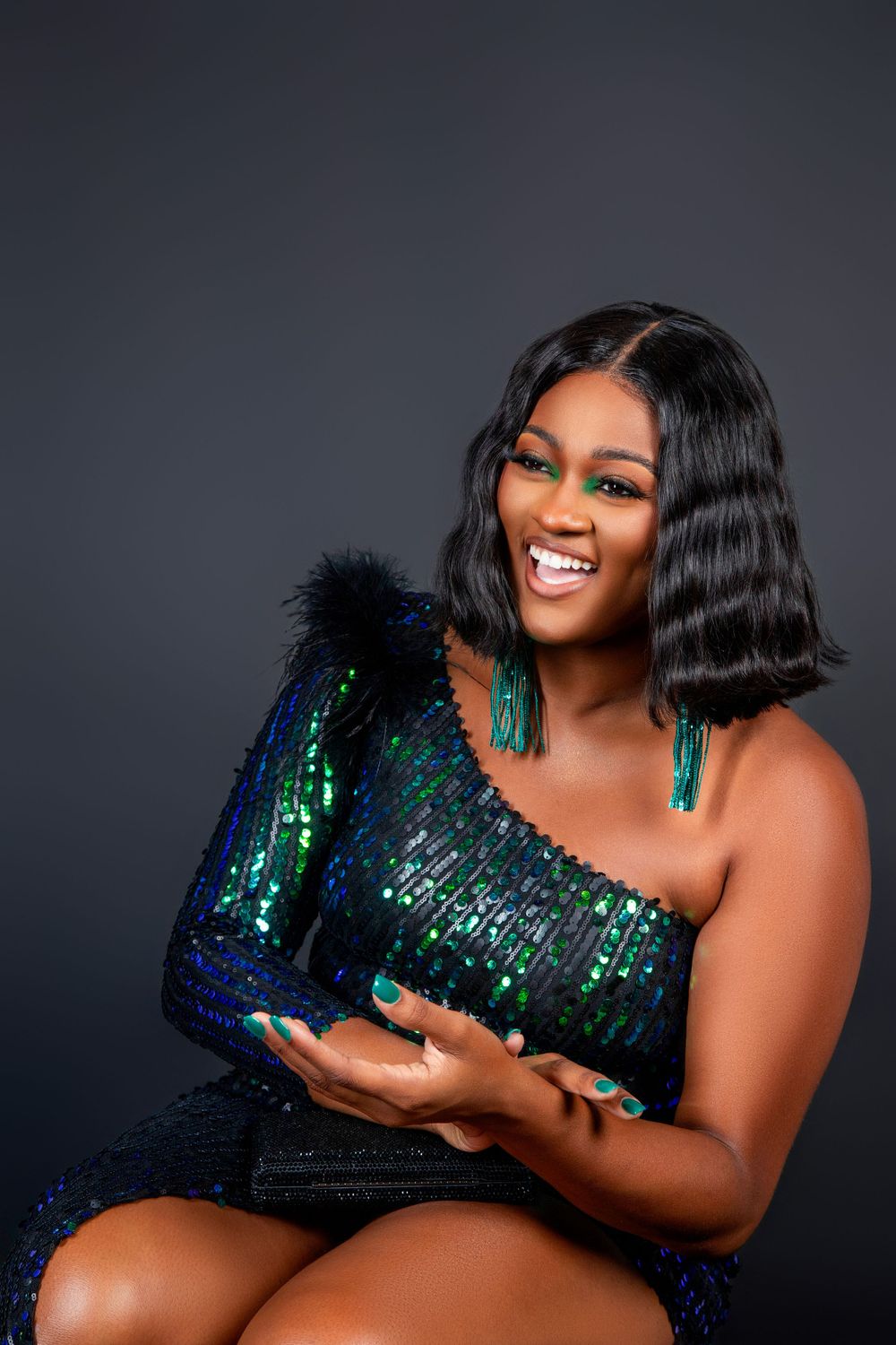 Portrait of person wearing sparkly blue-green sequin dress against dark background.