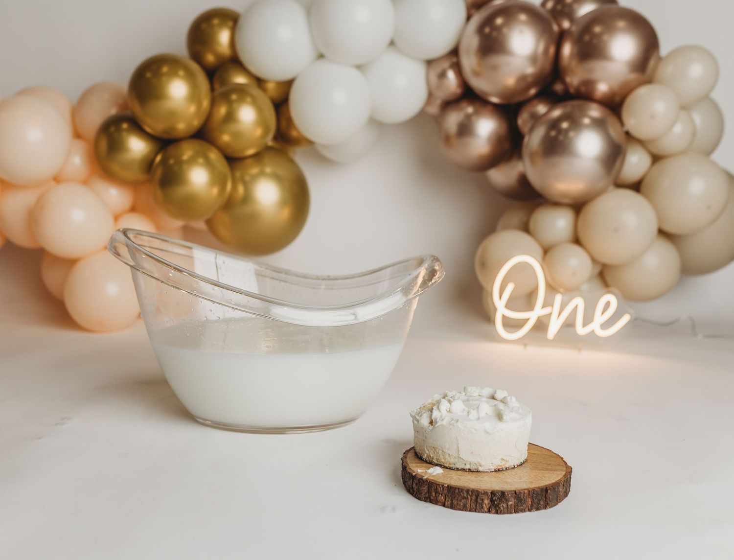 Minimalist cake smash setup with balloon arch and vintage white basin.
