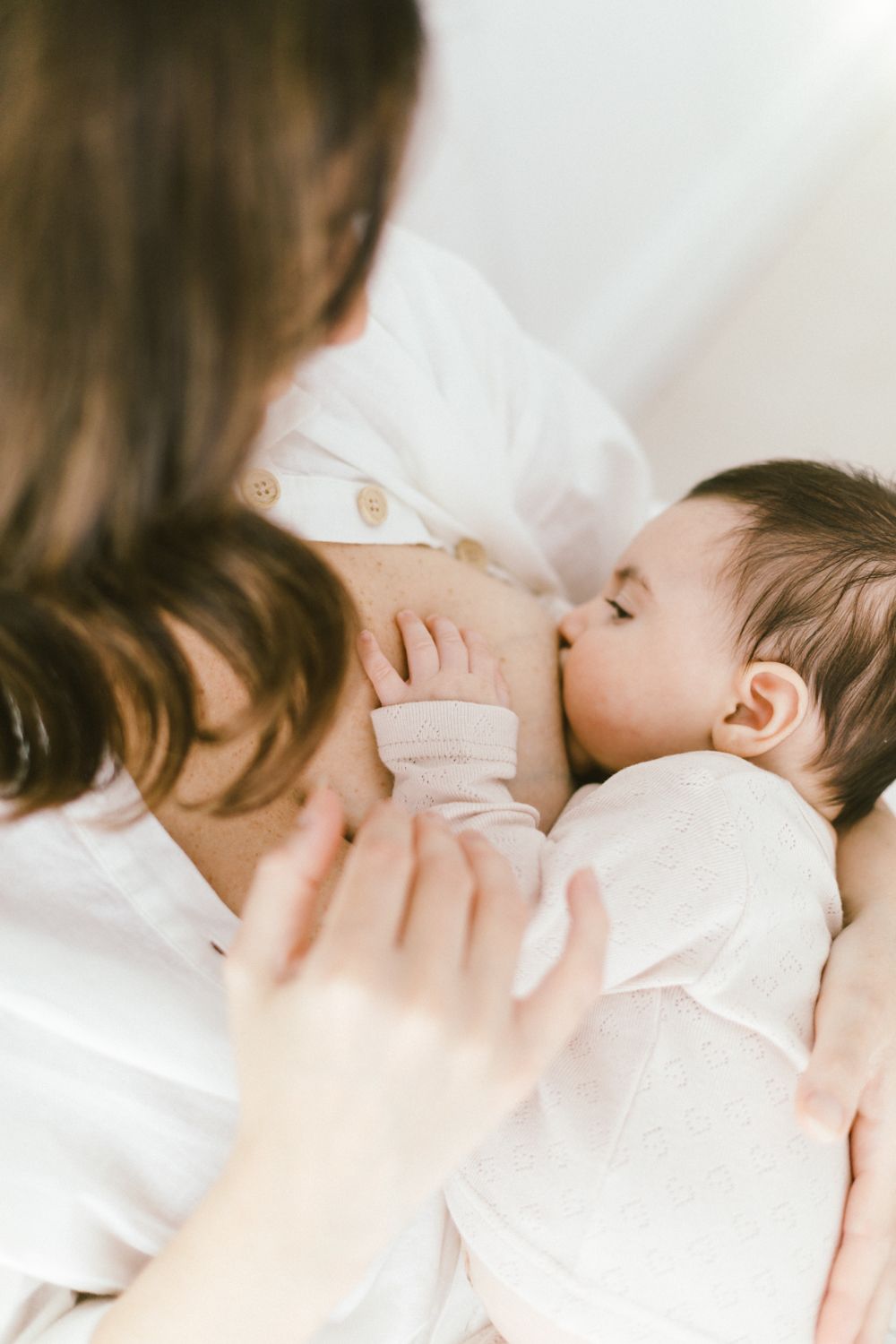 Close-up nursing portrait showing gentle connection between caregiver and baby.