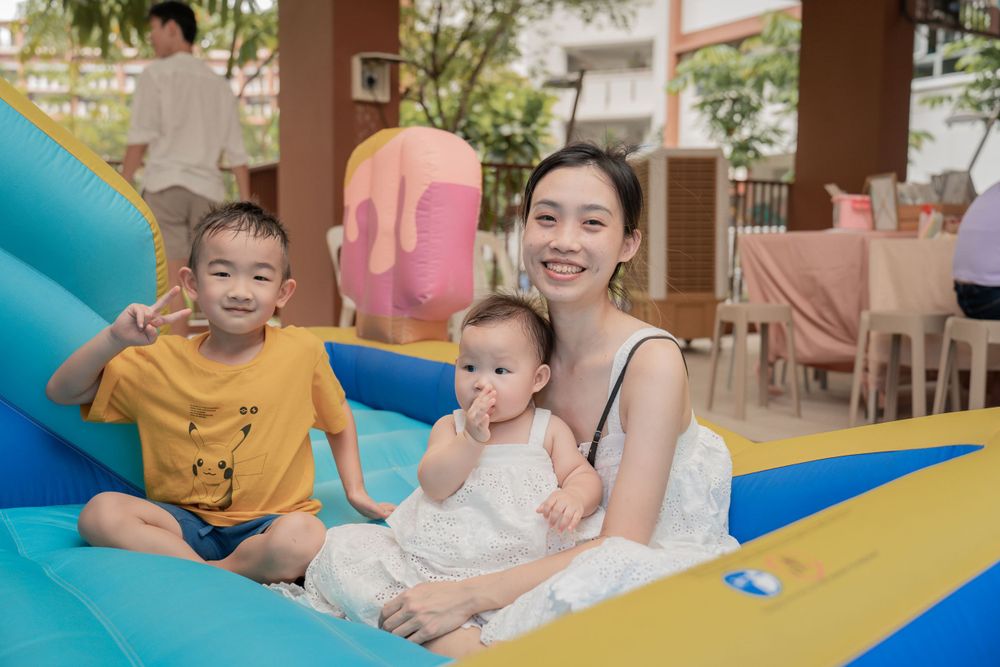 Happy family playing together on a blue inflatable bouncy castle at a party.
