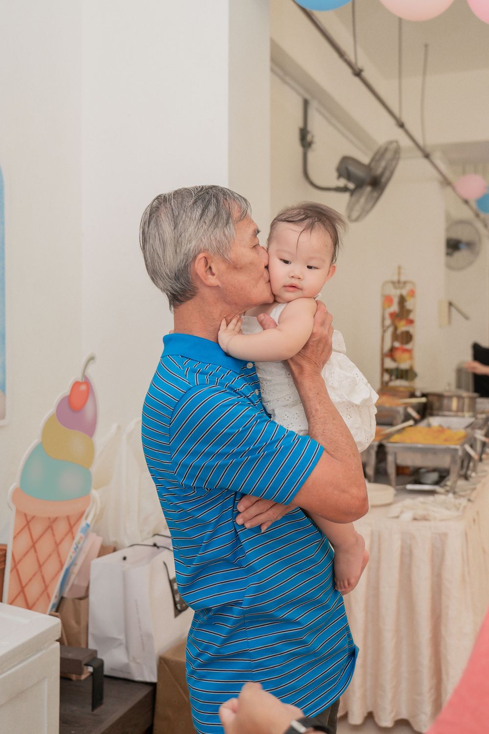 Tender moment captured during a family celebration with decorative balloons in background.