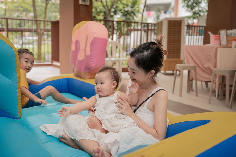 Family enjoying time together on a colorful inflatable play area with pink decorations.