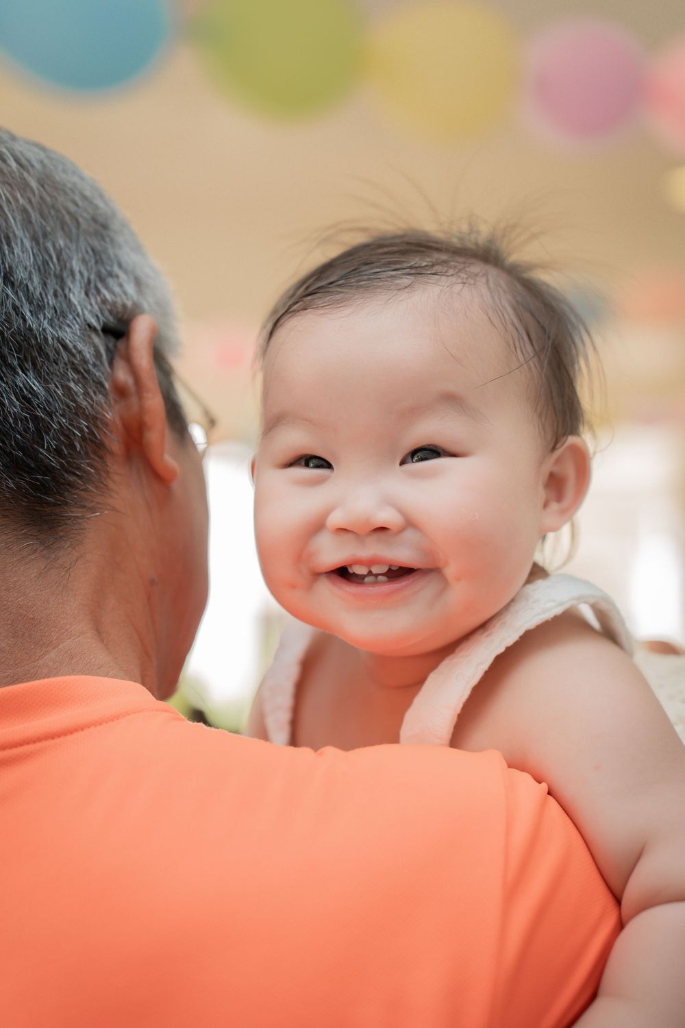 A smiling baby in white dress enjoying a festive celebration.