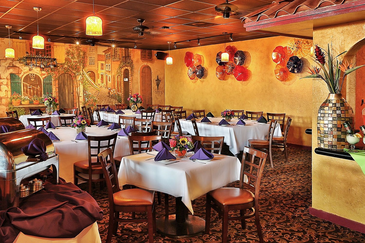 Cozy restaurant interior with warm lighting, painted murals, and traditional table settings.