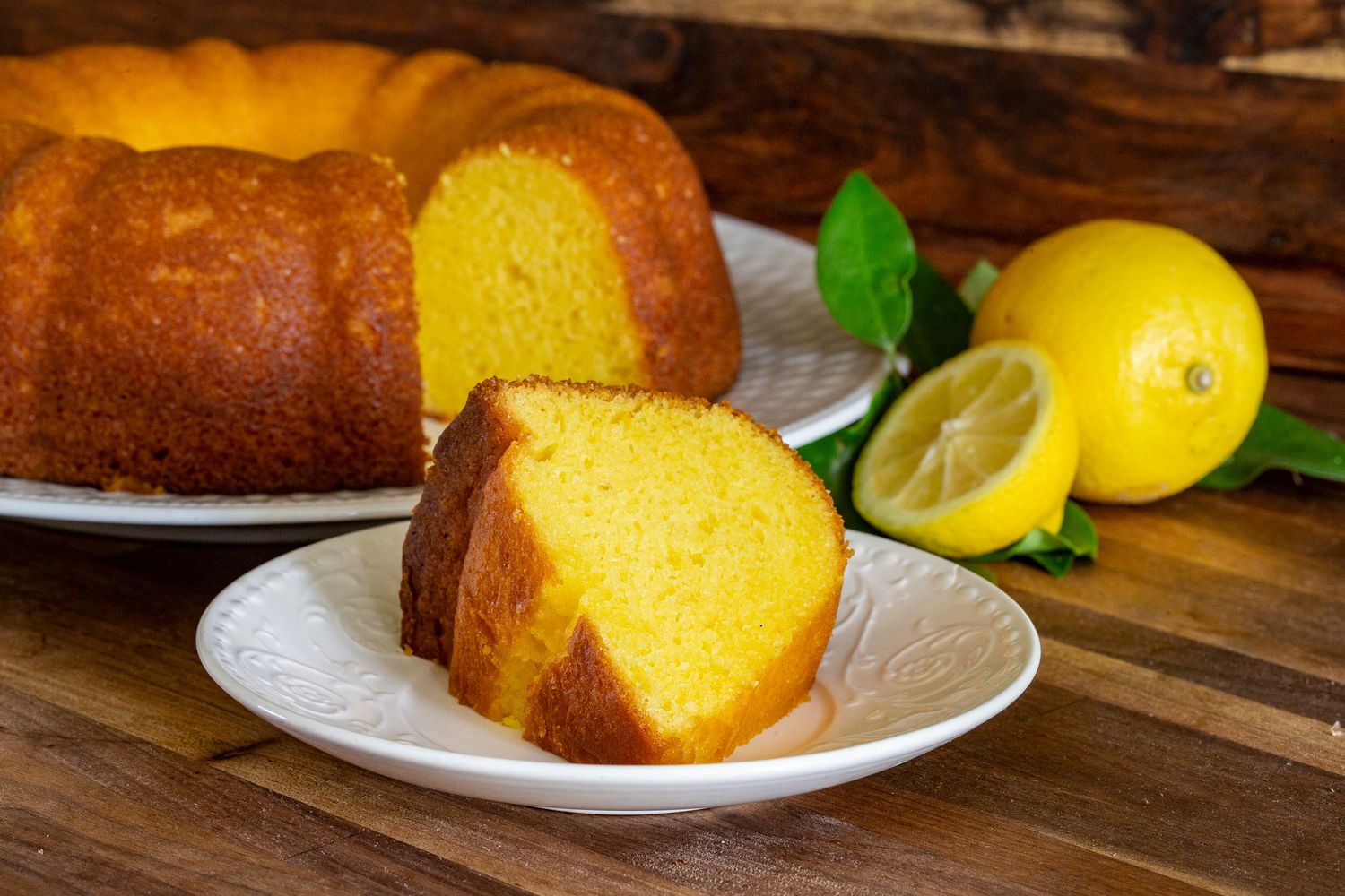 Sliced lemon pound cake with fresh citrus fruits on a white plate.