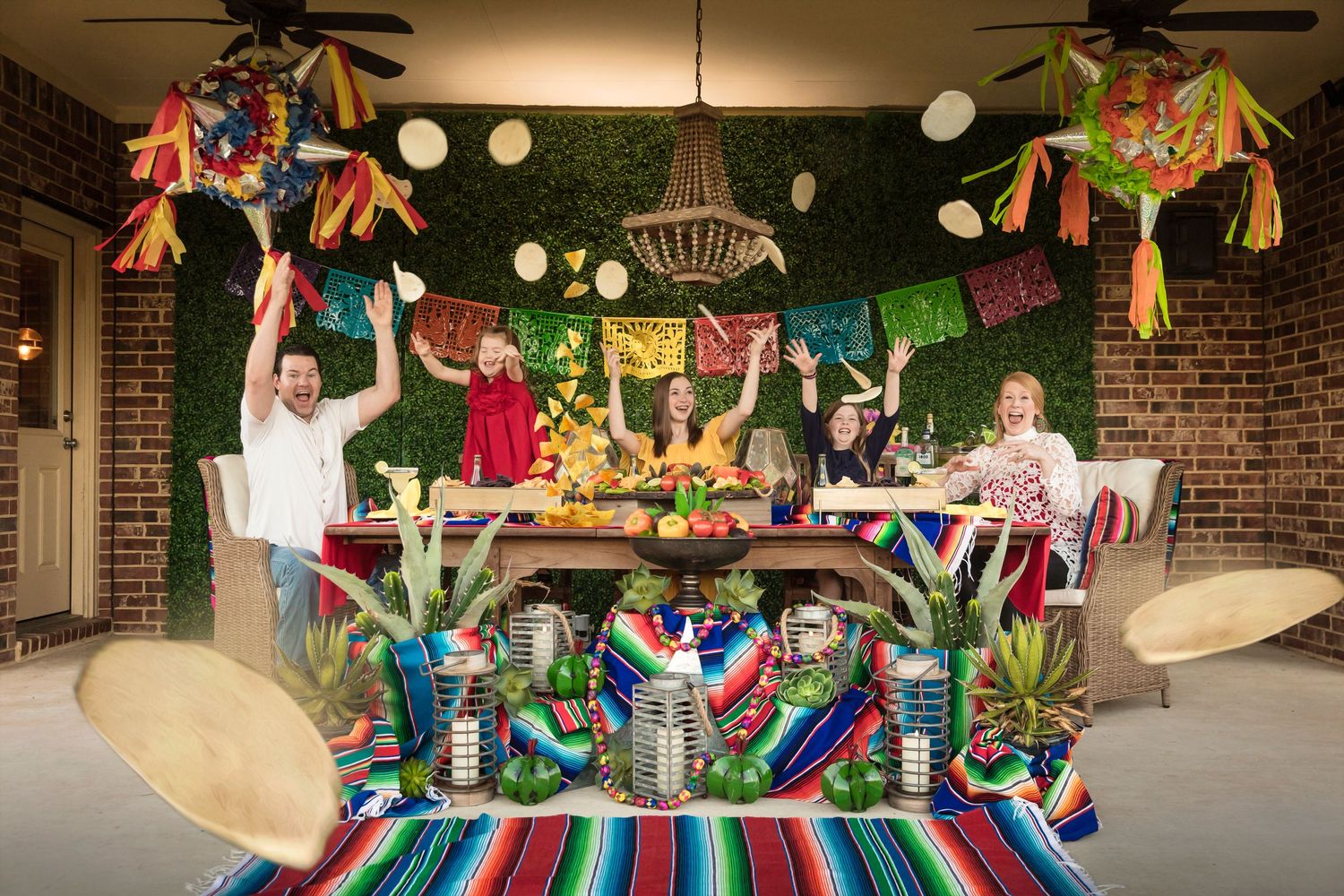 Colorful Mexican fiesta themed party decorations with papel picado banners and string lights on a porch.