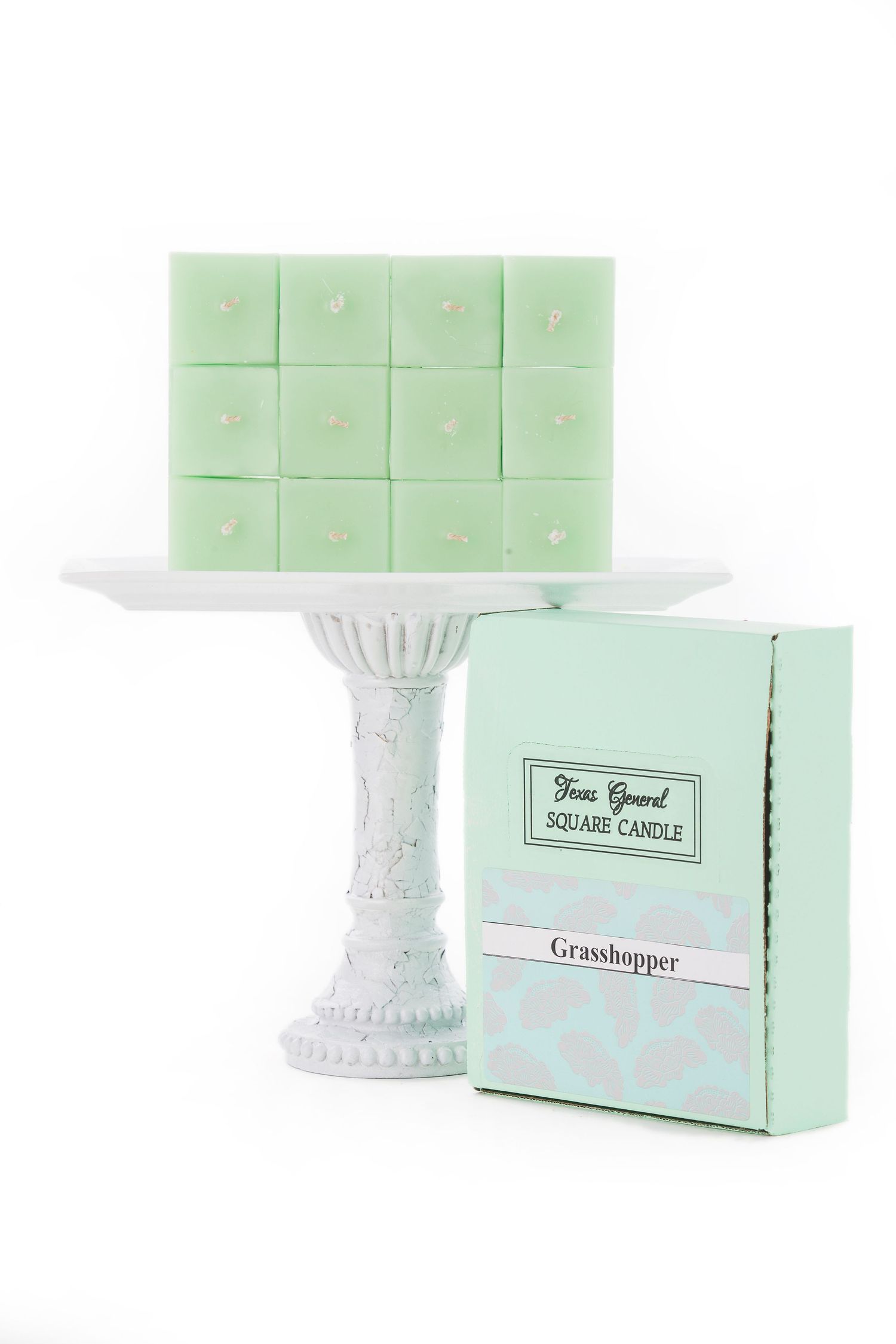 Mint green scented wax melts displayed on a decorative white pedestal with matching packaging.