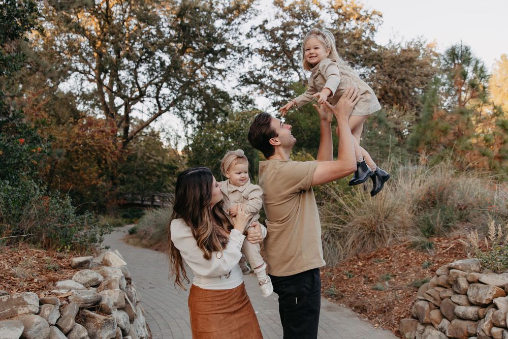 Family playing together outdoors on stone path surrounded by fall foliage.