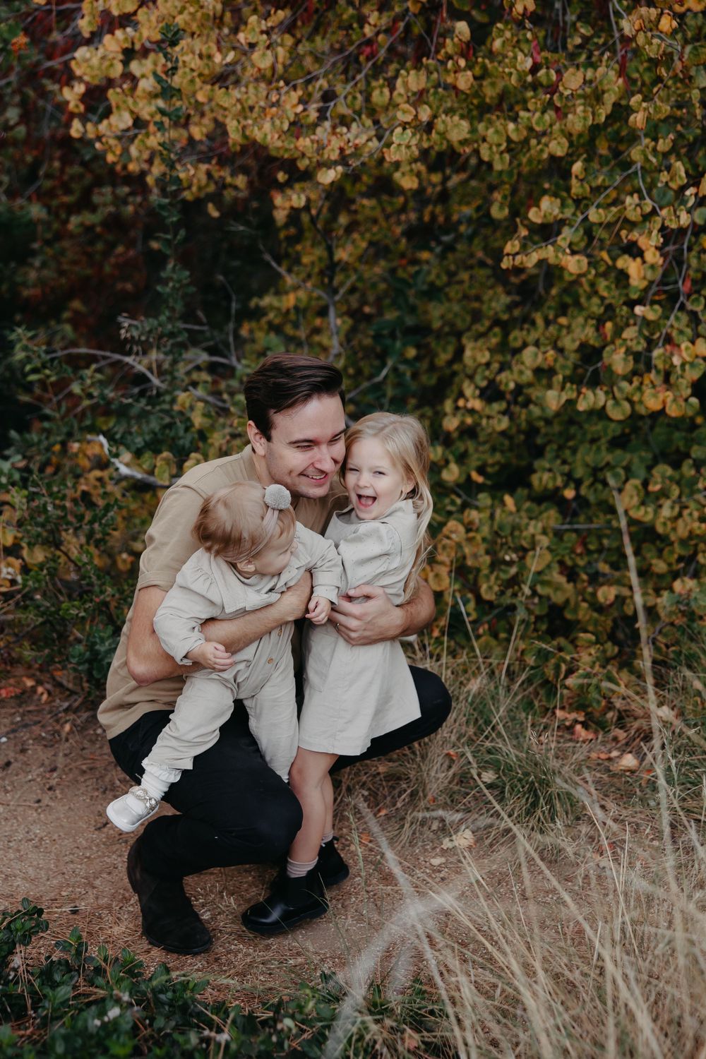 A sweet family moment captured in autumn with fall foliage creating a warm natural backdrop.