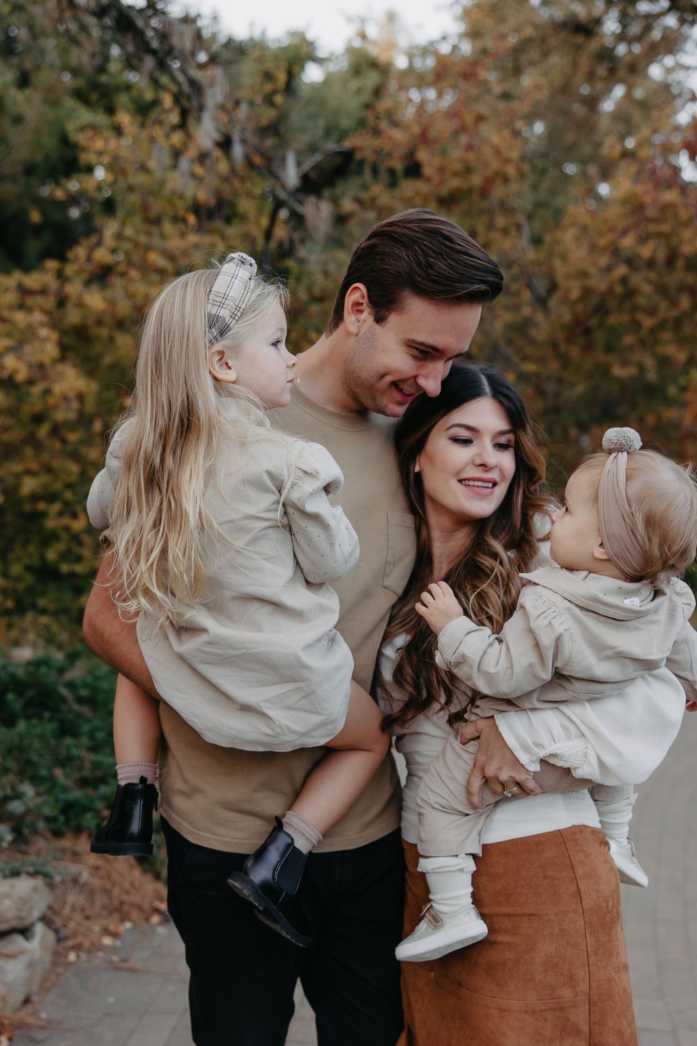 Happy family moment captured outdoors with matching neutral-toned clothing.