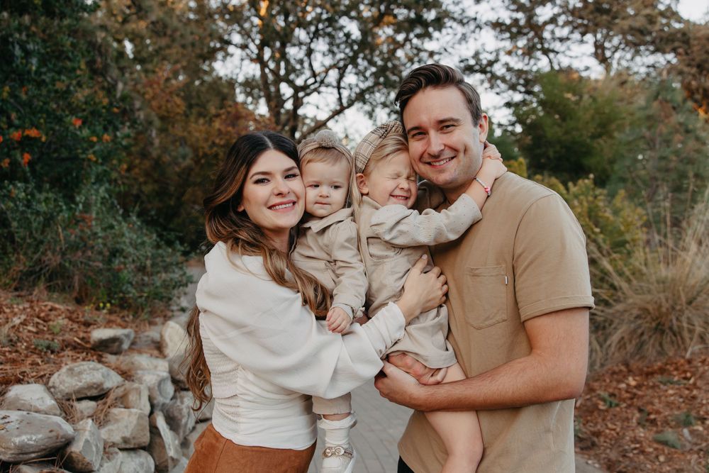 A warm family portrait captured outdoors in coordinating neutral tones.