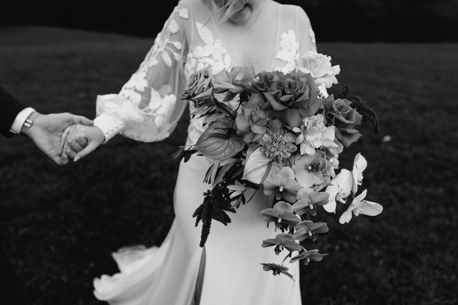 Black and white photo of bride holding elegant white floral bouquet.