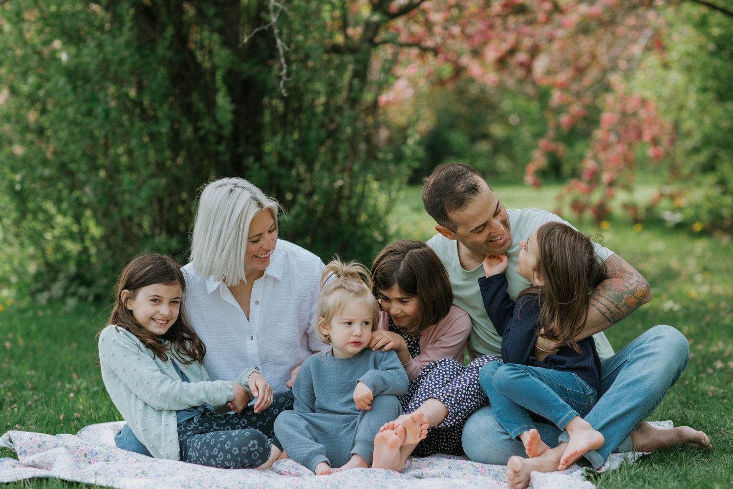 Family enjoying a relaxing picnic together on a blanket in a lush green garden setting.