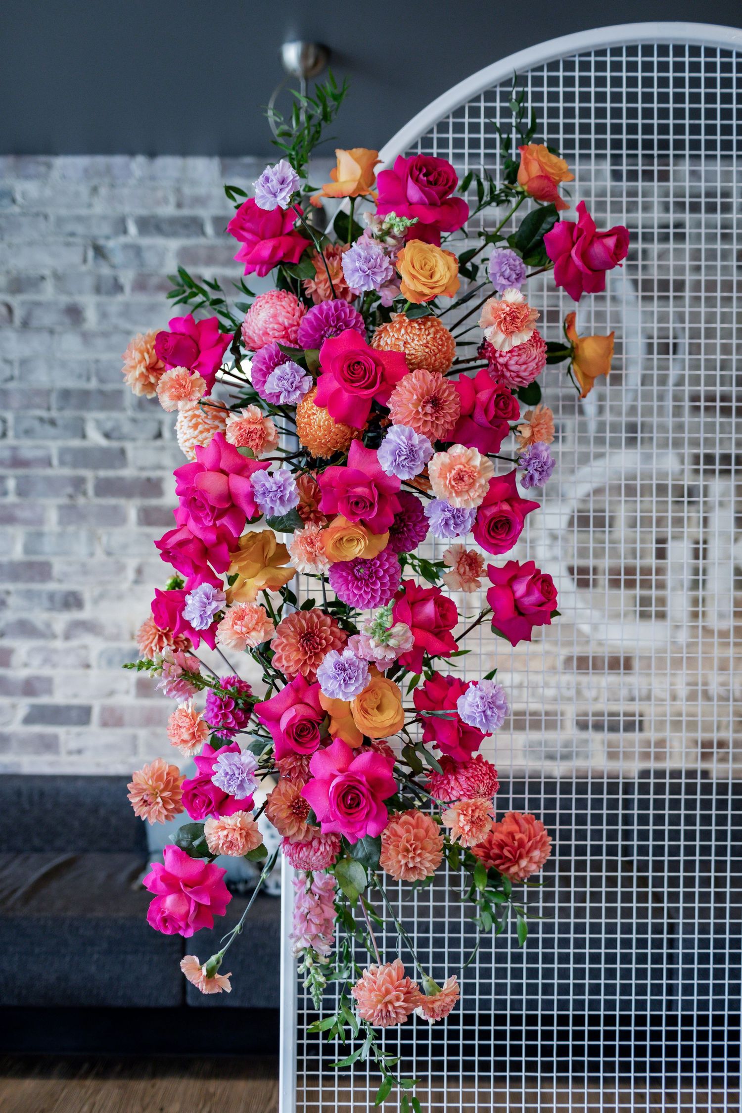 Dramatic floral arrangement featuring hot pink roses and peach dahlias cascading down white mesh divider.