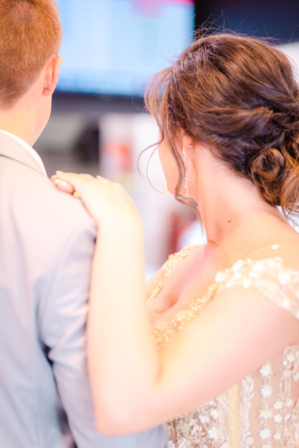 Young woman in a yellow dress resting her hands on her partner's shoulder and looking the other way.