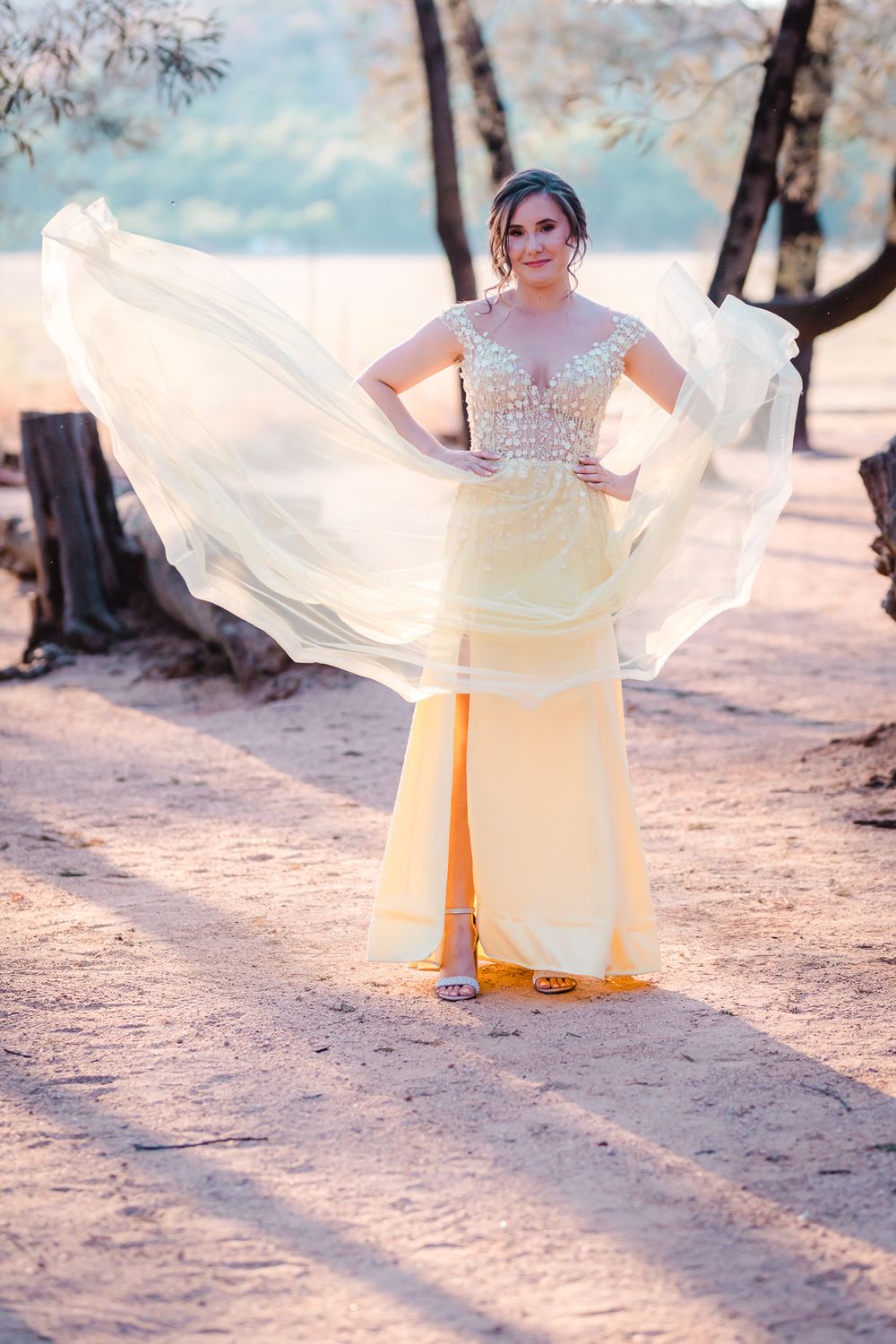 Young dark haired woman with hands on hips and yellow lace floating in the wind