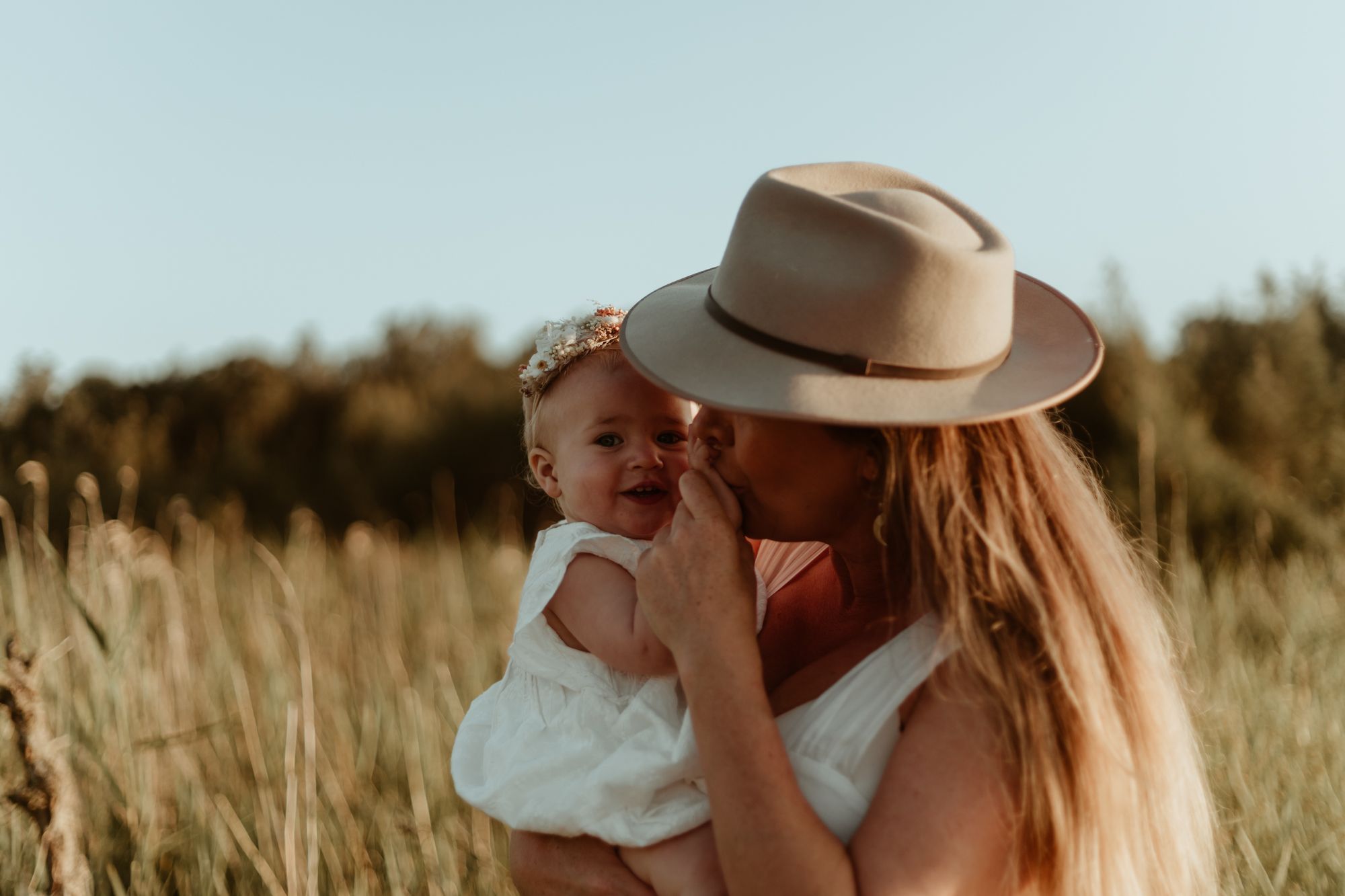 An intimate moment shared between adult and baby in a sun-drenched field.