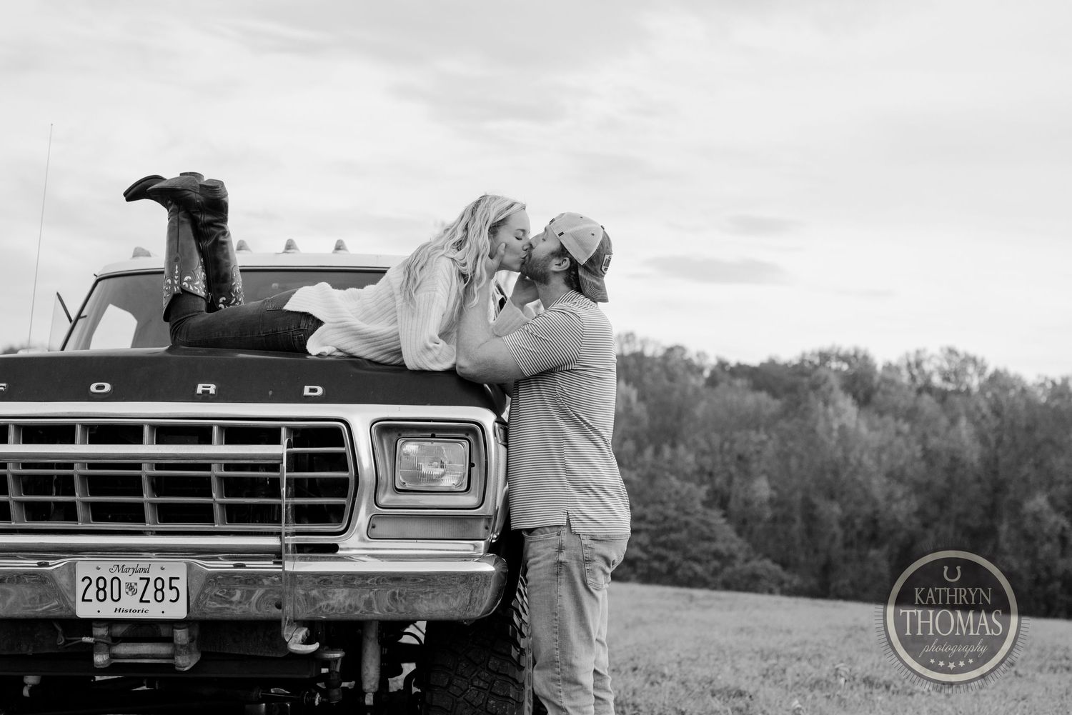 Black and white photo of a tender moment between a couple against a classic Ford pickup truck.