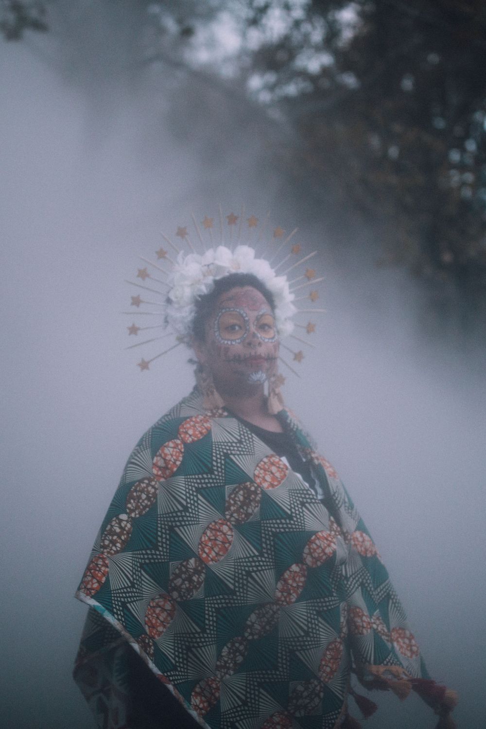 Latinx Black femme wearing traditional Dia de los Muertos facepaint, flower crown, and clothing in fog, Boston TX