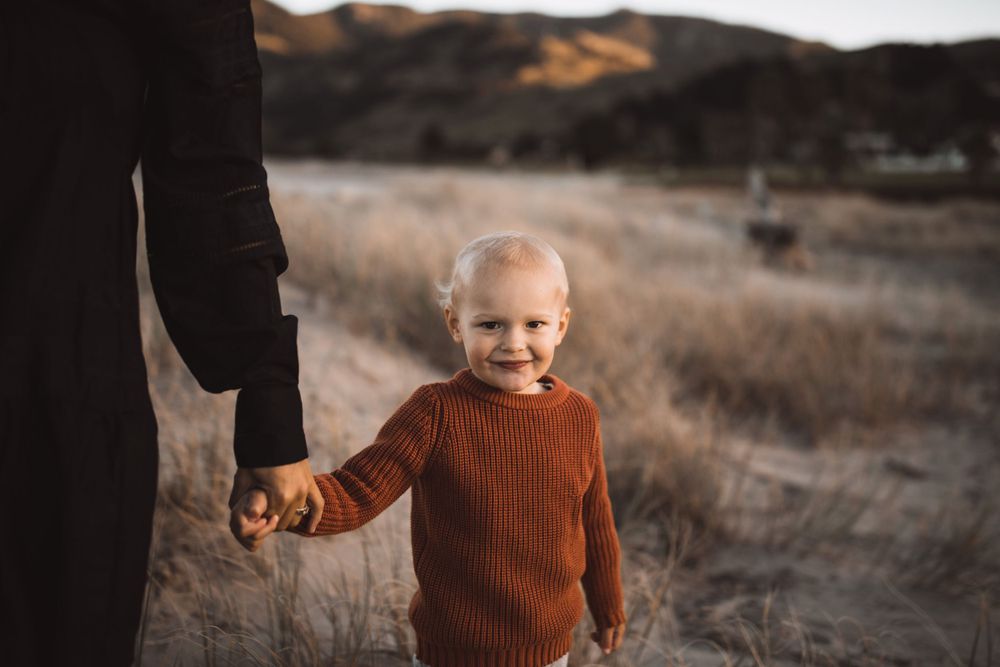 Children exploring dried grass field during golden hour photo session.