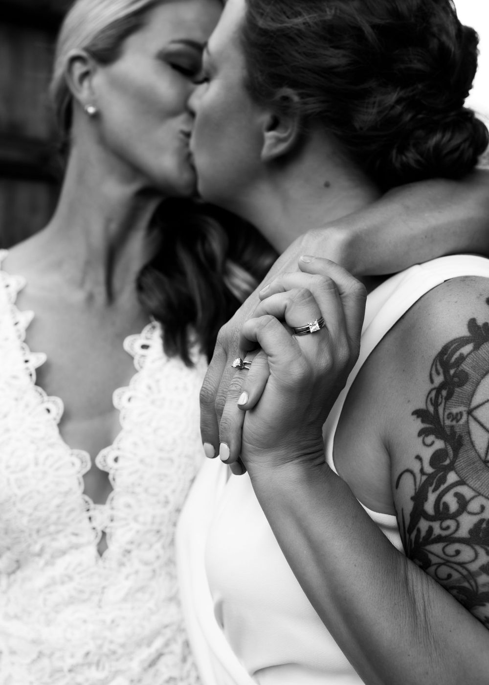 Black and white intimate wedding portrait showing couple's rings and tattoo detail.