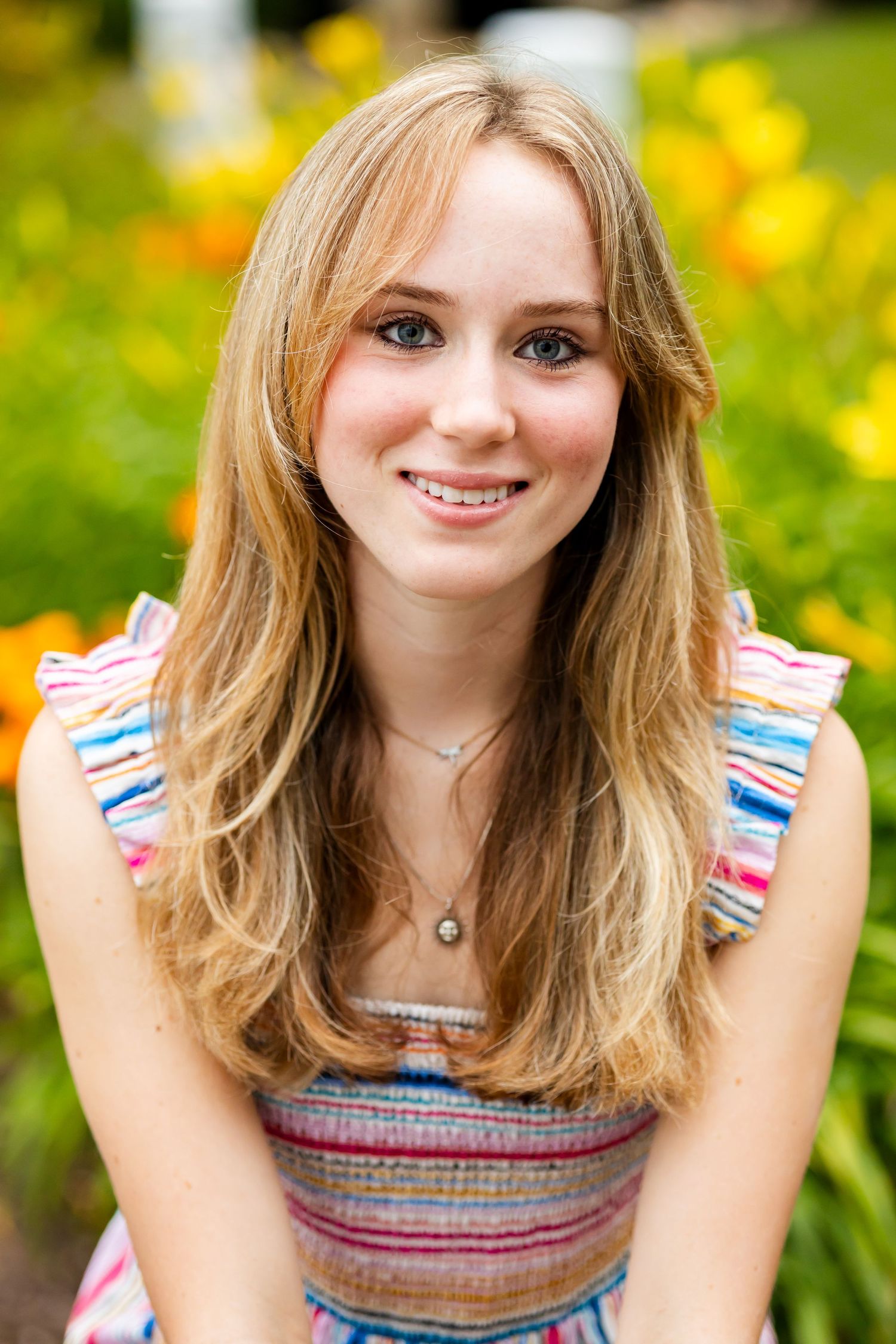 Portrait in summer garden with blooming yellow daylilies and colorful striped top.