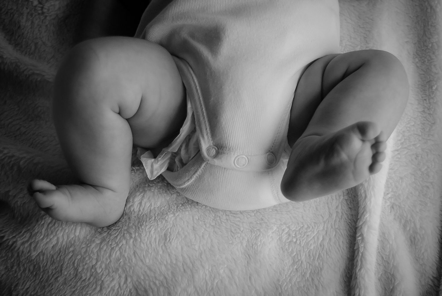 Black and white close-up of sleeping newborn's tiny feet.