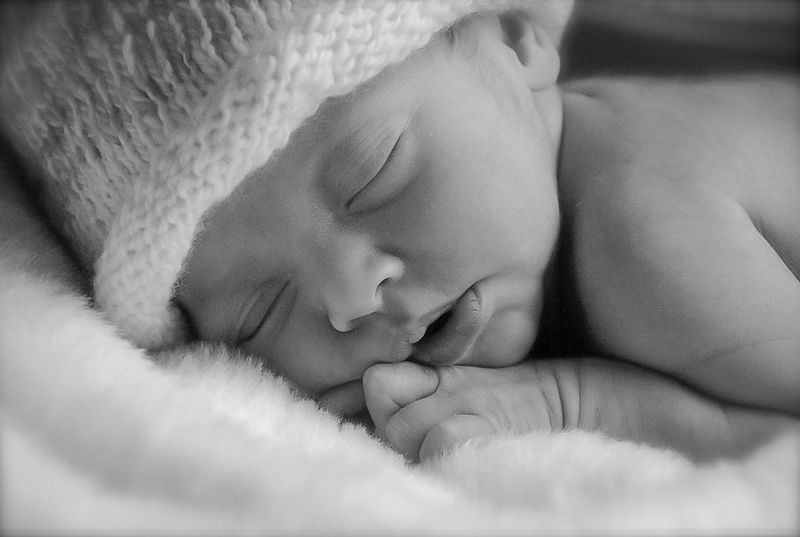 Black and white close-up of sleeping newborn in knit hat.