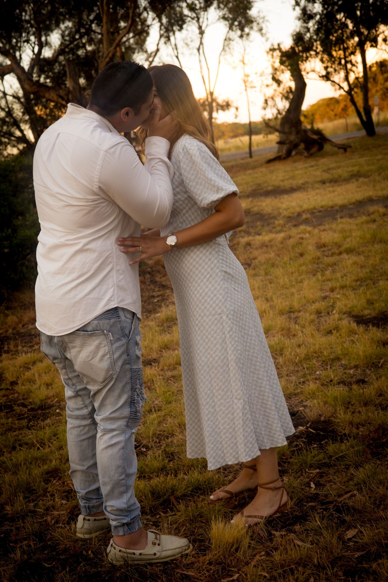 Intimate family moment captured during sunset in field with glowing warm light.