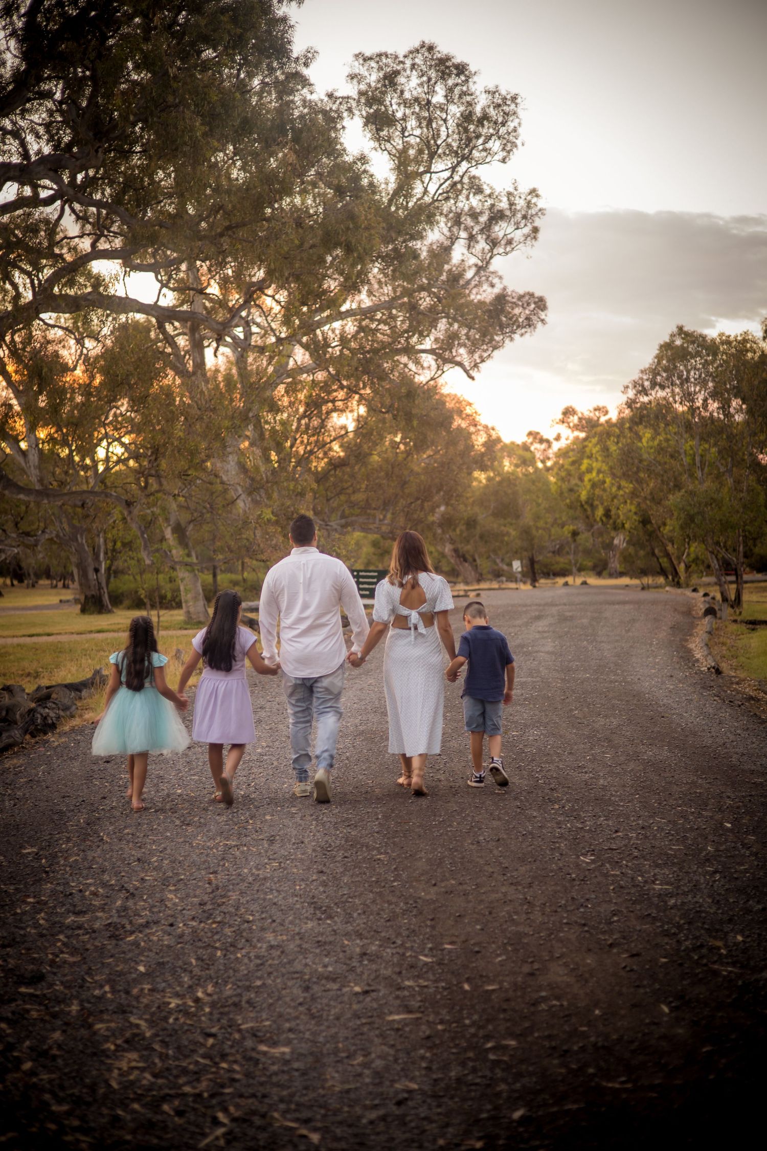 Group walking together at sunset on a gravel path surrounded by gum trees in an Australian landscape.
