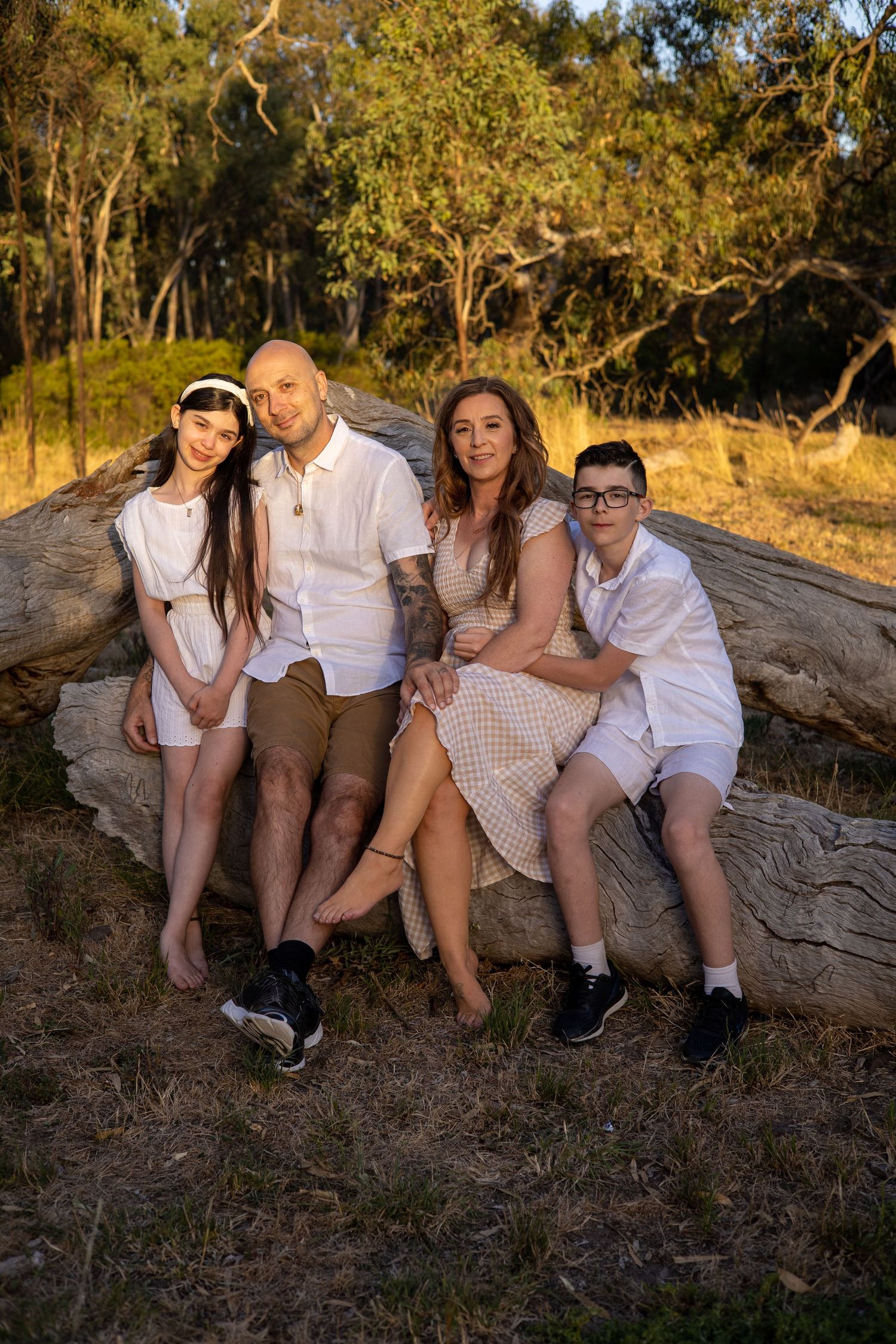 Family poses together on fallen log during golden hour photoshoot.