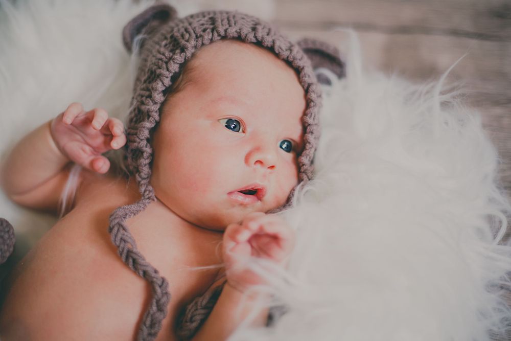 Gray knit winter hat on white textured background in muted tones.