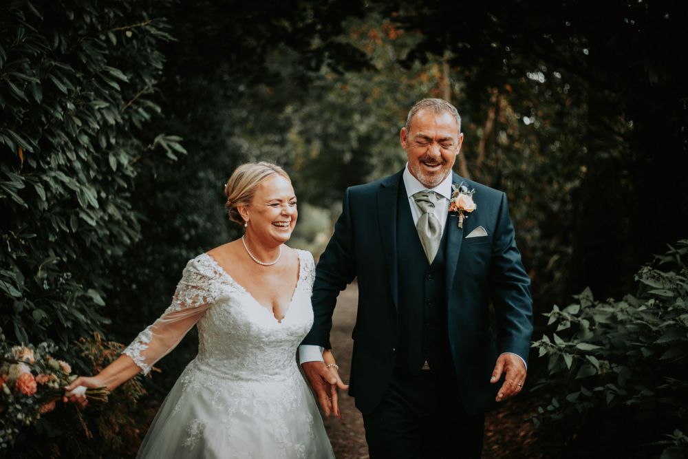 Bride and groom share joyful laughter during outdoor autumn wedding photography session.