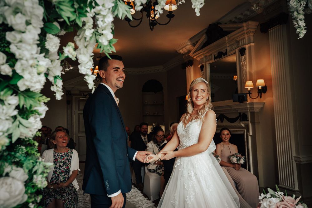 Wedding couple dancing under elegant white floral decorations and chandeliers.
