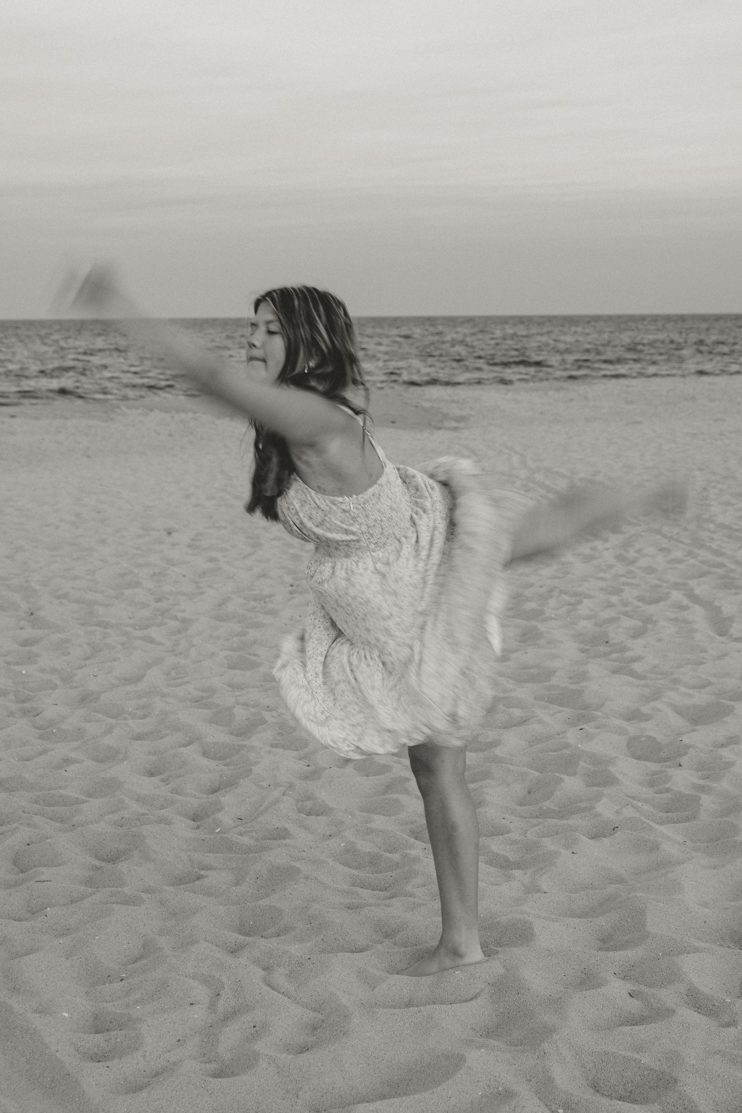 Silhouette of a dancer in a flowing dress twirling gracefully on the beach at sunset.