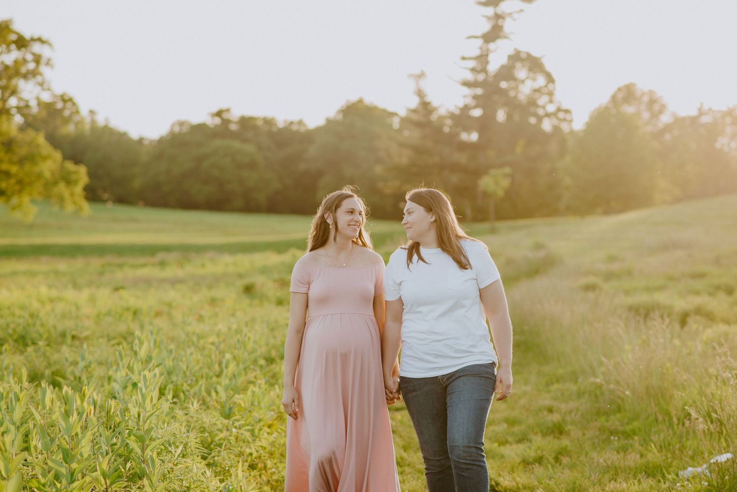 Same sex couple walking during maternity session at Golden hour